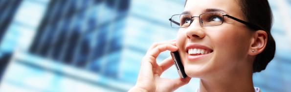 Donna sorridente al telefono davanti a un edificio.