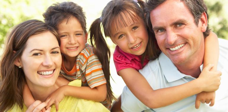 Happy family outdoors with two smiling children.